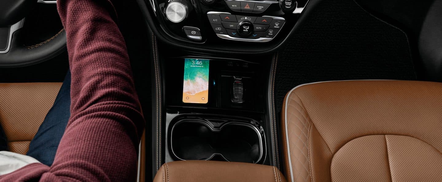 The center stack in a 2024 Chrysler Pinnacle with a smartphone in the wireless charging pad.